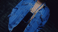 a man wearing a jean jacket and holding a cell phone