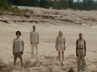 a group of people standing on top of a sandy beach