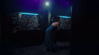 a woman standing in a dark room in front of a mirror