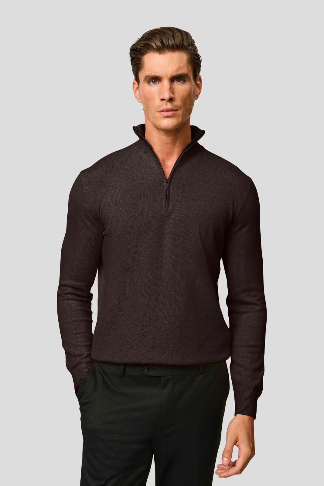 a man in a brown sweater and black pants