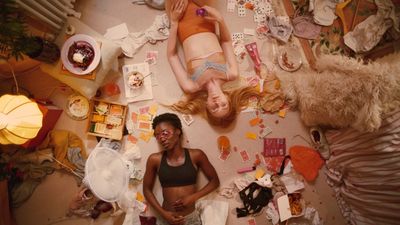 two women laying on the floor surrounded by clutter