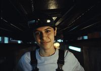 a woman wearing a hat and suspenders standing in a room