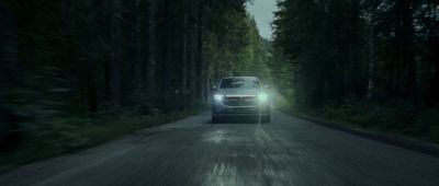 a white car driving down a forest road