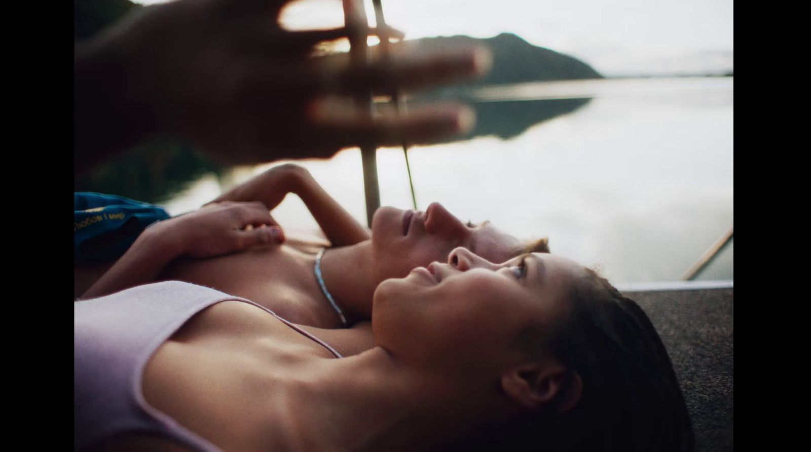 a woman laying on the ground next to a body of water