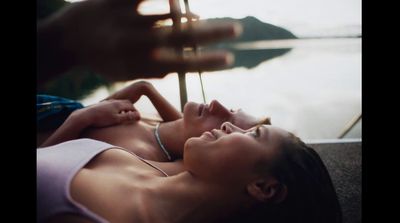 a woman laying on the ground next to a body of water