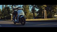 a man riding on the back of a motorcycle down a street