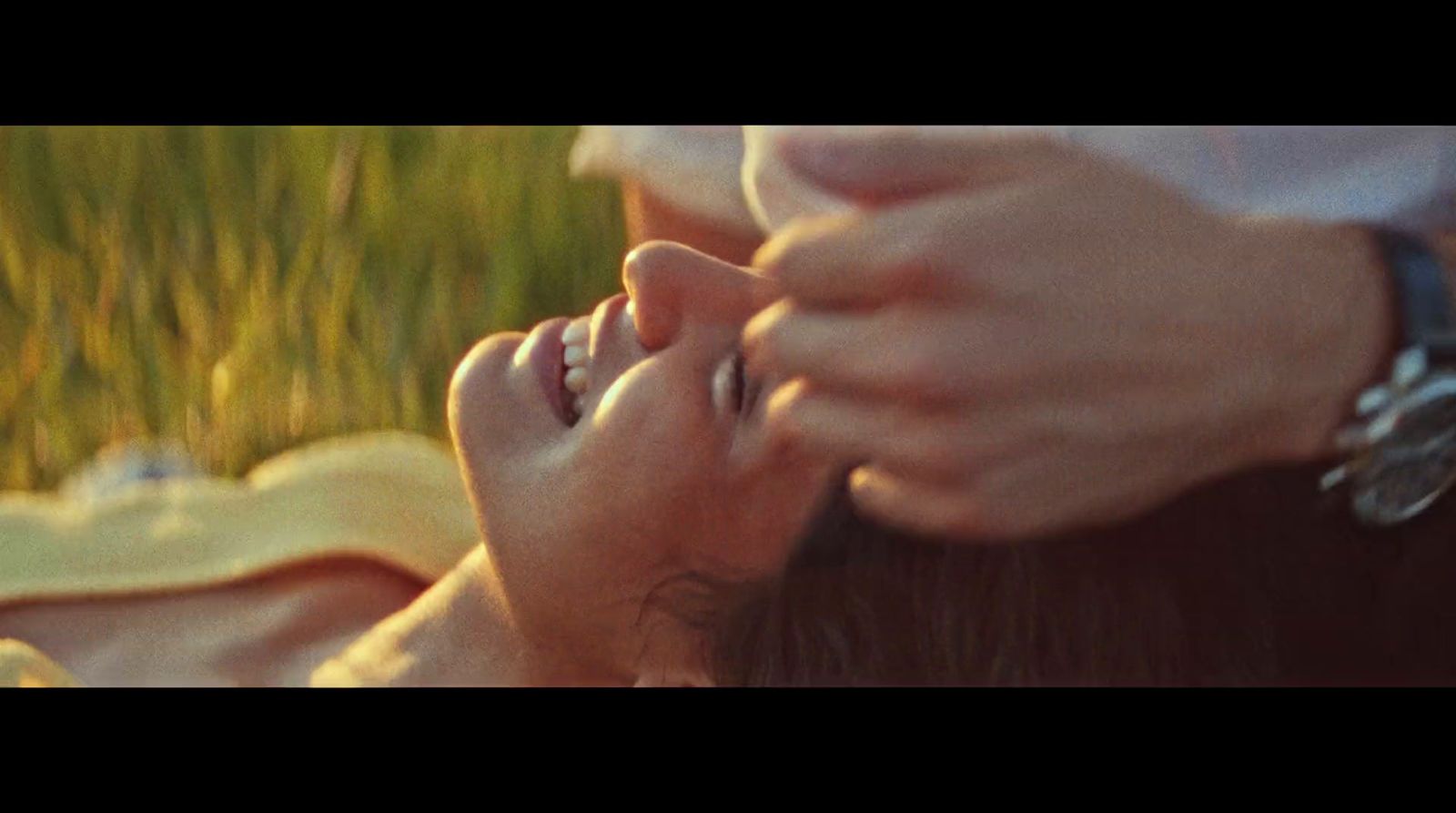 a woman laying on top of a grass covered field