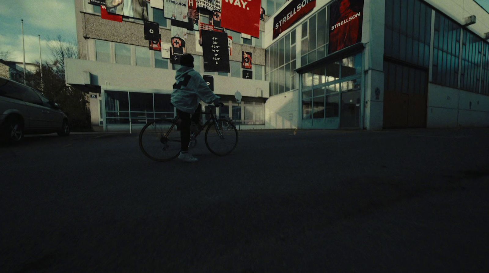 a man riding a bike down a street next to a tall building