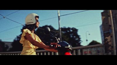 a woman in a yellow dress riding a scooter