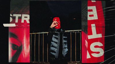 a person wearing a red mask standing in front of a fence