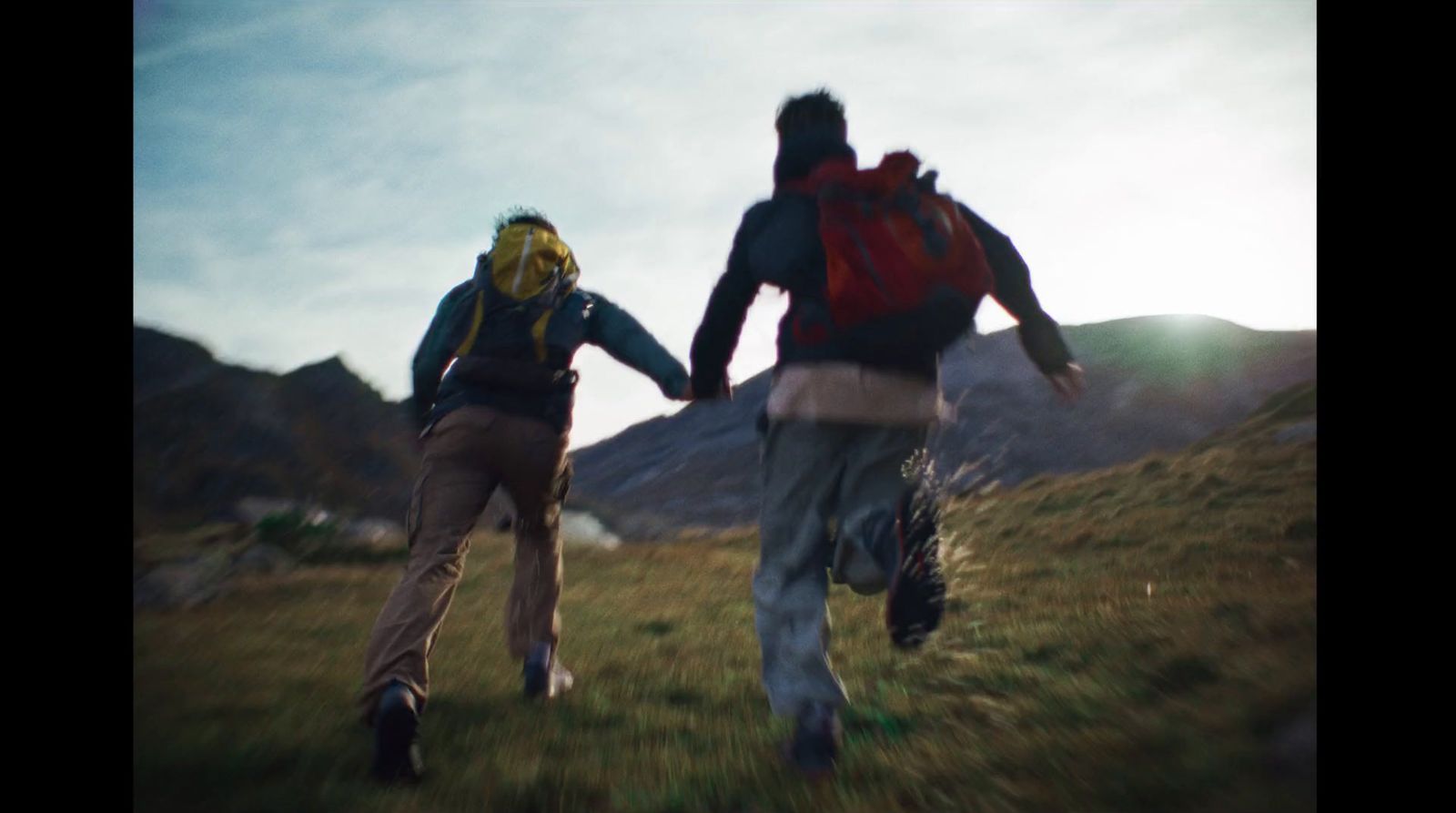 a couple of people walking across a grass covered field