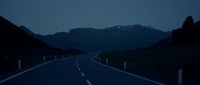 an empty road with mountains in the background