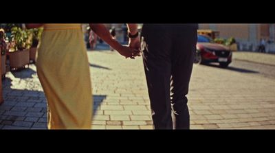 a man and a woman holding hands walking down a street