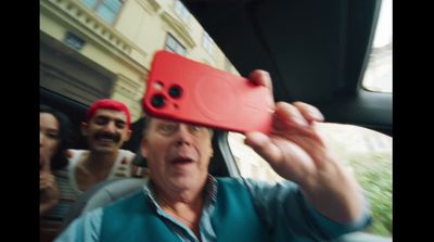 a man holding up a red phone case to his face