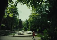 a woman walking through a park next to trees