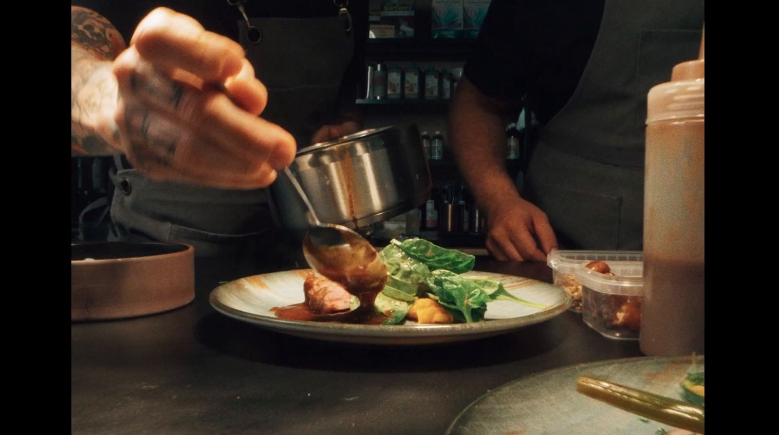 a person pouring sauce on a plate of food