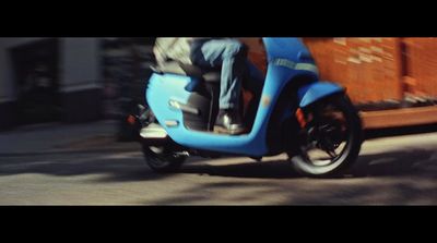 a man riding a blue scooter down a street