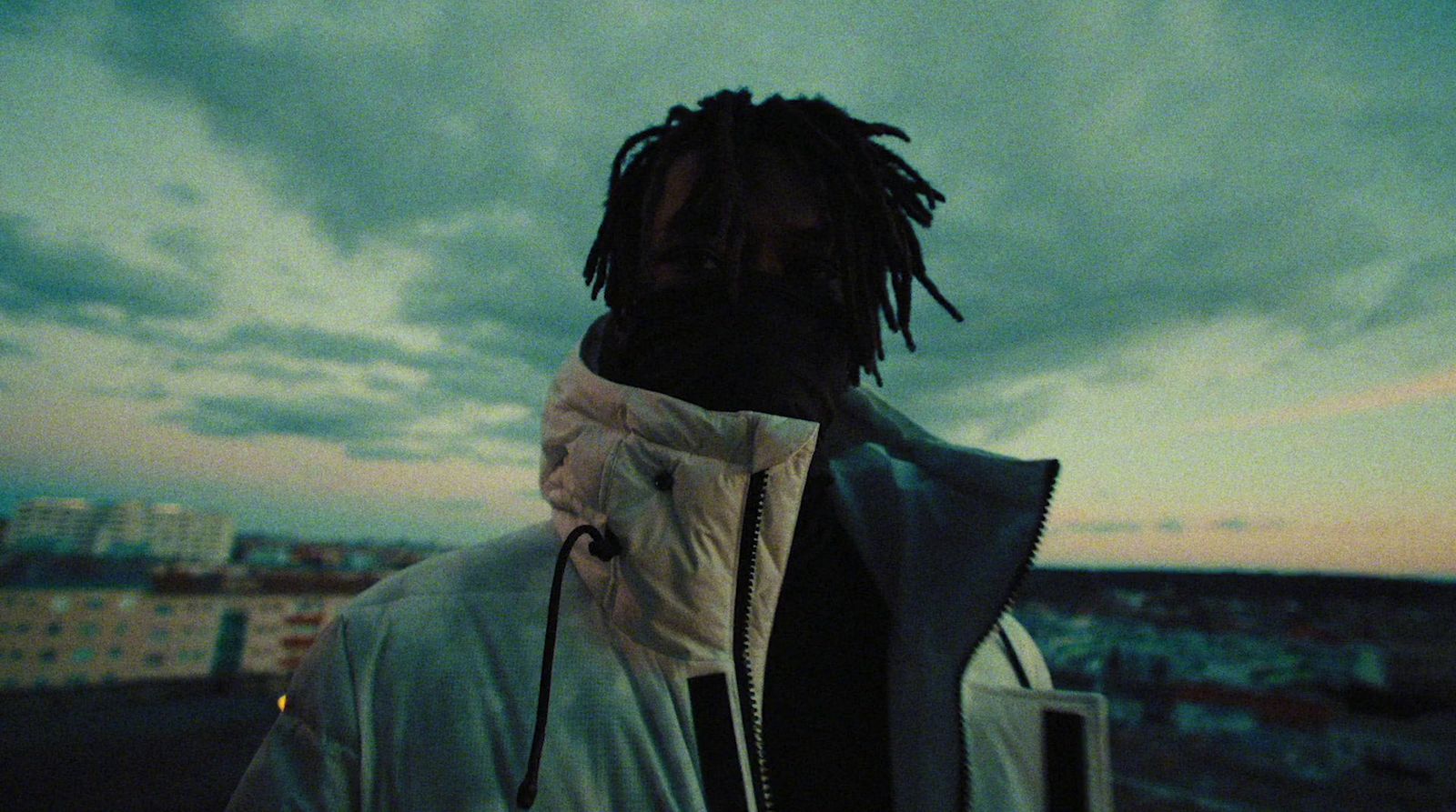 a man with dreadlocks standing on a roof