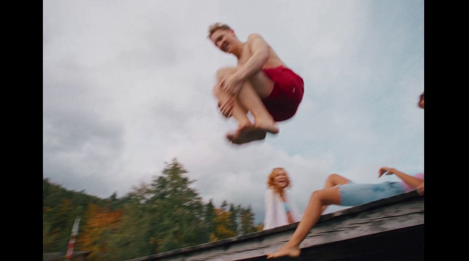 a man in a red swimsuit jumping off a roof