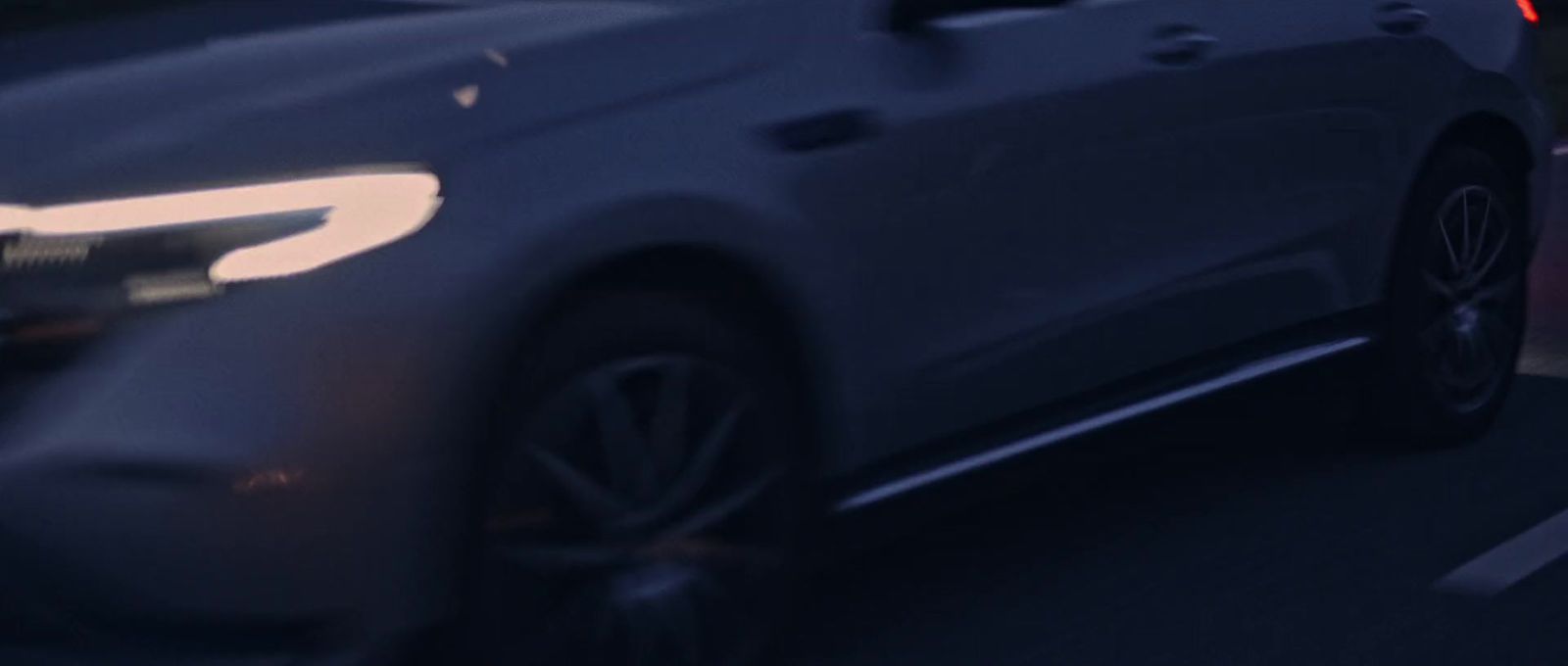 a white car driving down a street at night