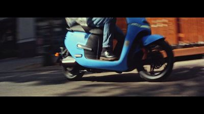 a man riding a blue scooter down a street