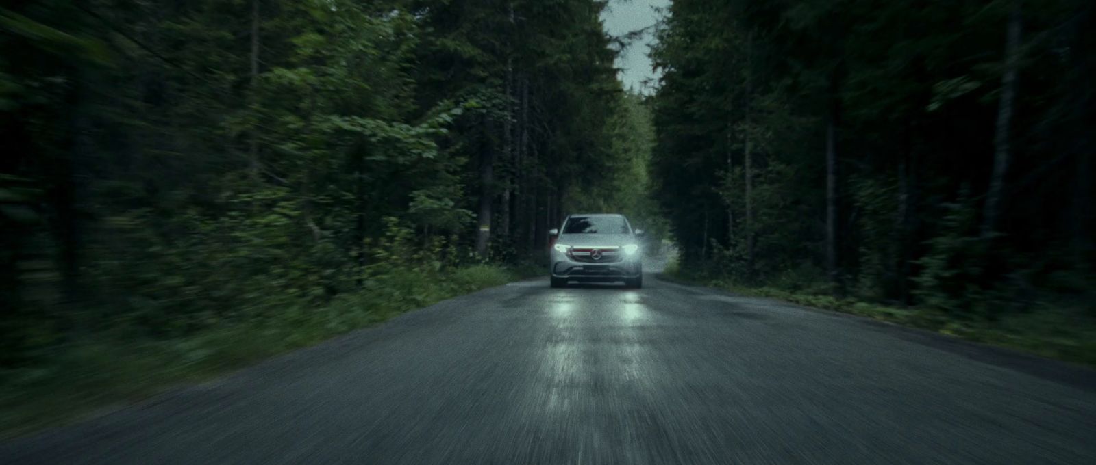 a car driving down a road surrounded by trees