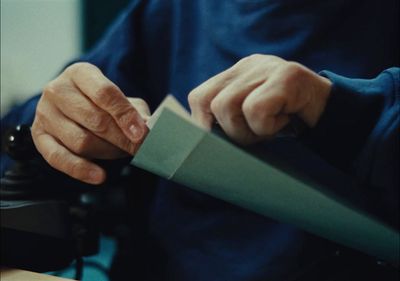 a person is cutting a piece of paper with a knife