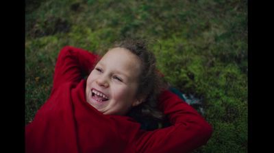 a little girl laying in the grass smiling