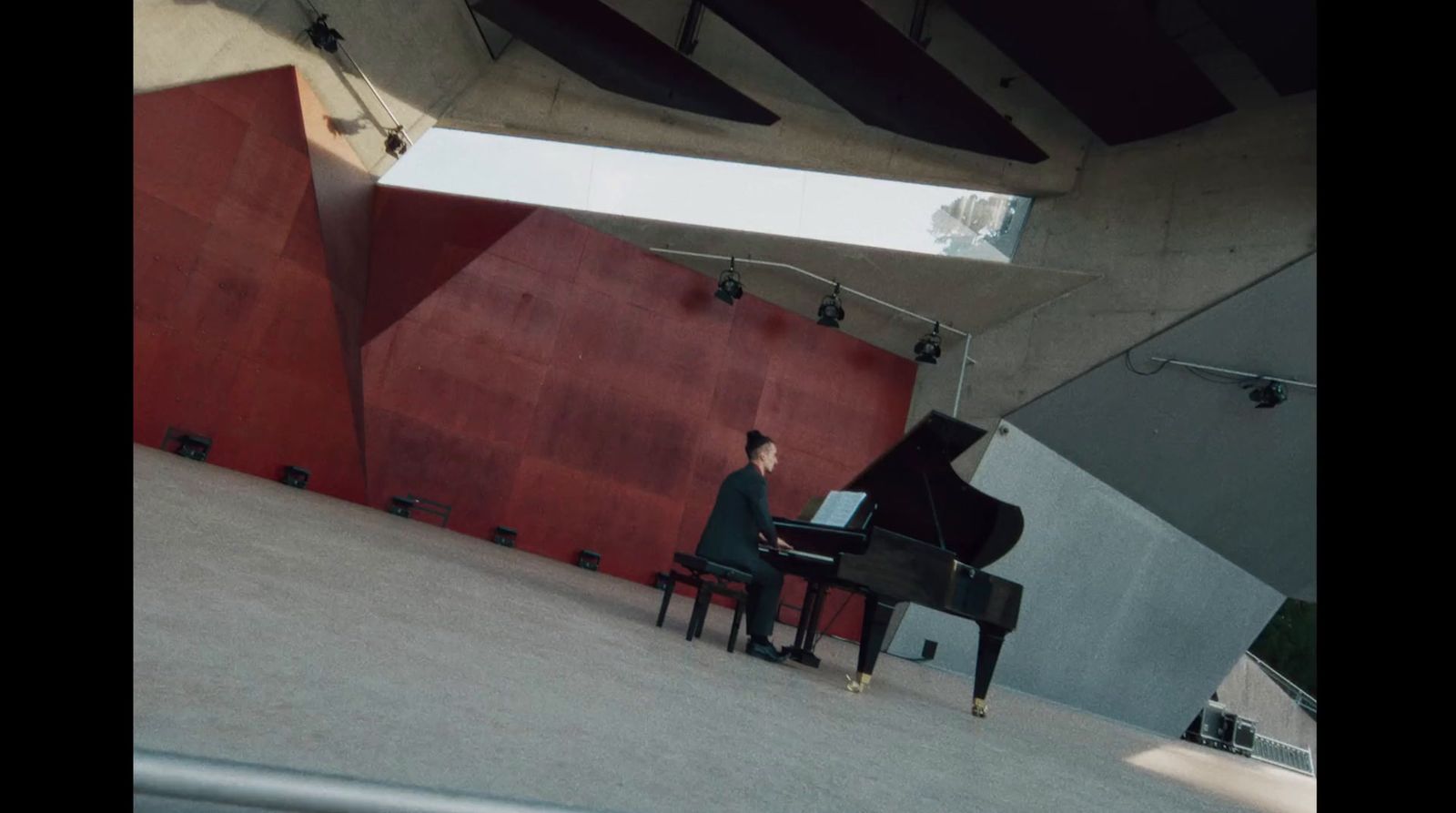 a man sitting at a piano in front of a red wall