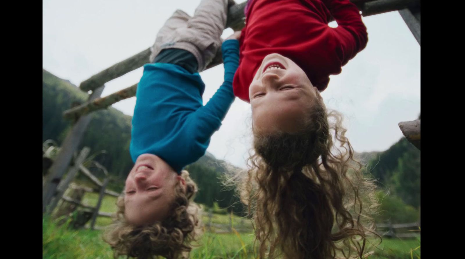 a couple of kids hanging upside down in the grass