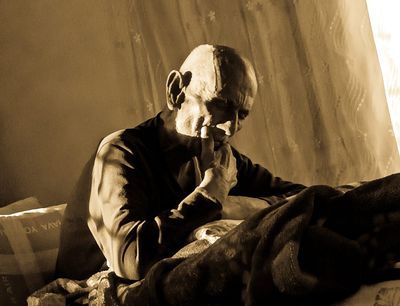 an old man sitting on a bed smoking a cigarette