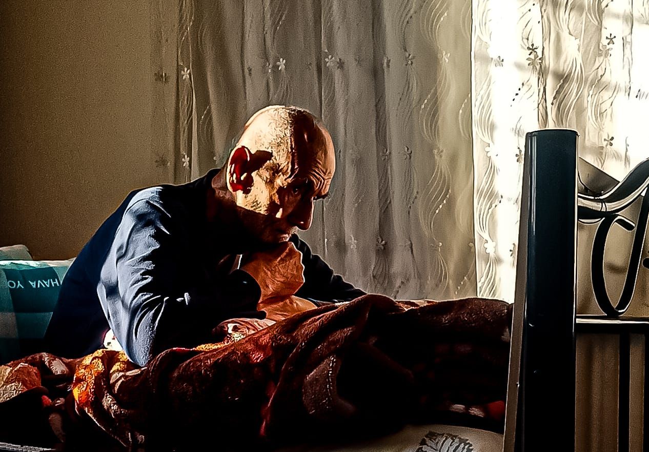 an old man sitting on a bed in a room