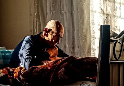 an old man sitting on a bed in a room