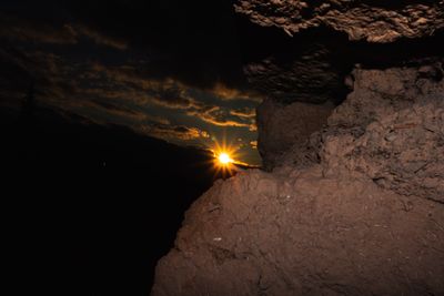the sun is setting over a rocky cliff