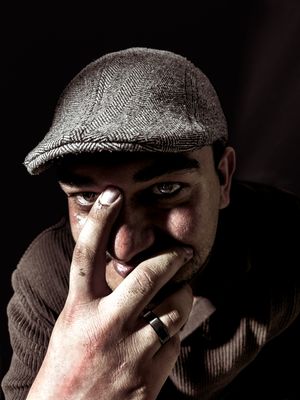 a man wearing a hat and holding his hand to his face