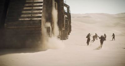 a group of people walking across a sandy field