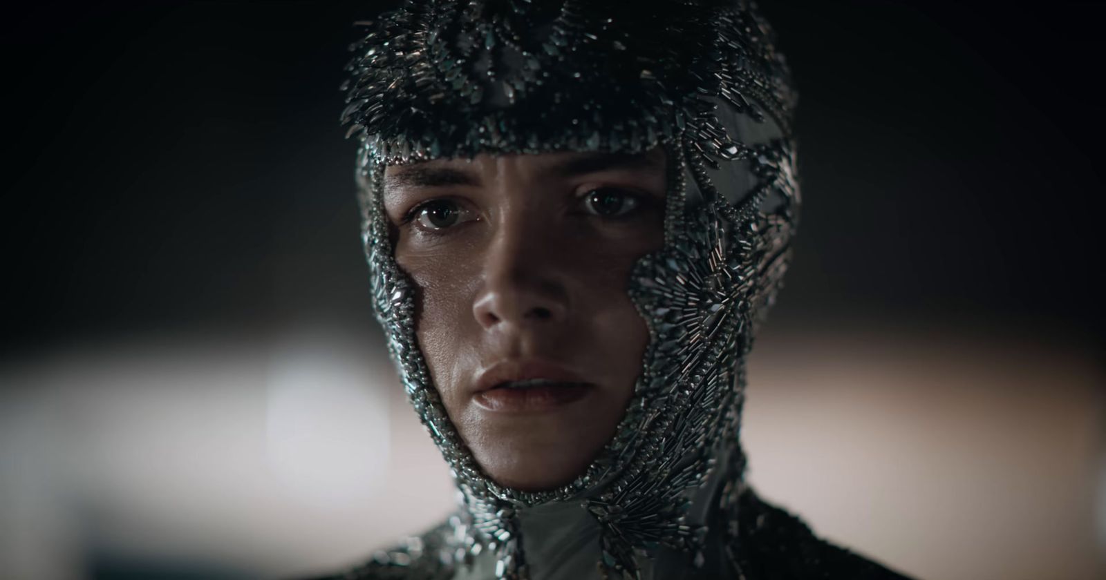 a woman wearing a silver headdress in a dark room