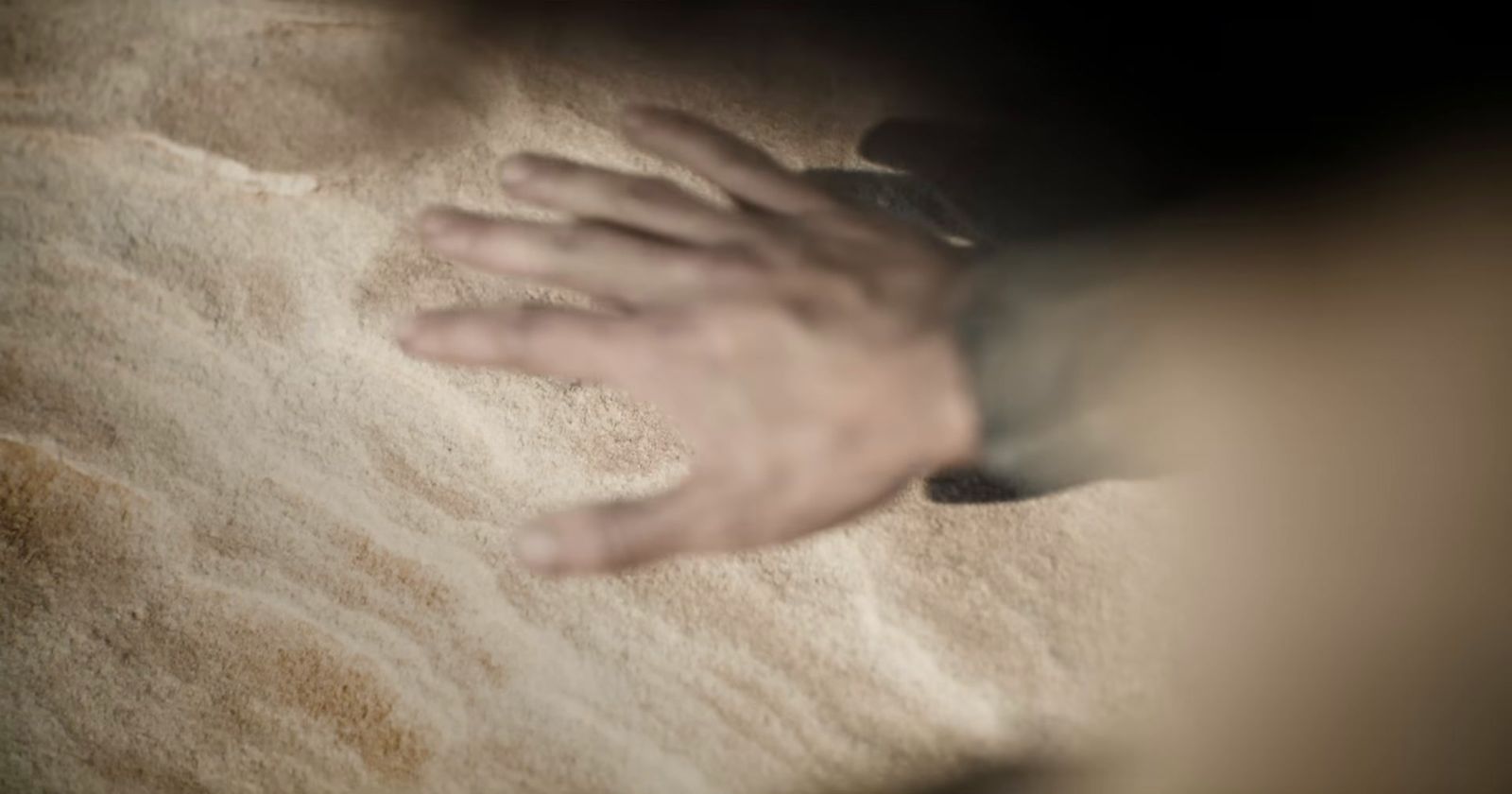 a person reaching for something in the sand