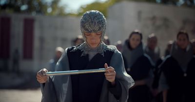 a woman in a silver headdress holding a stick