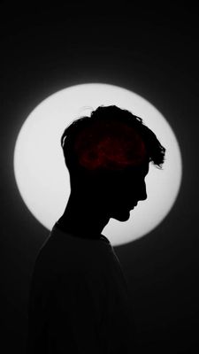 a silhouette of a man with a red head in front of a white circle