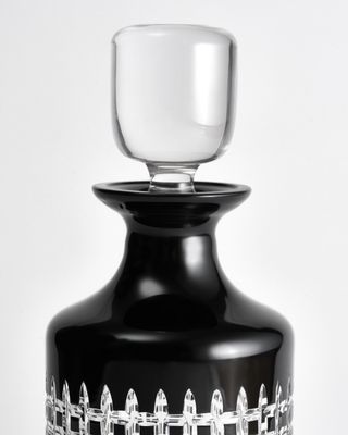 a black vase with a glass on top of it