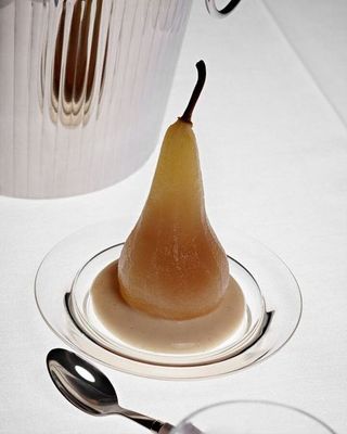 a pear on a plate with a spoon next to it