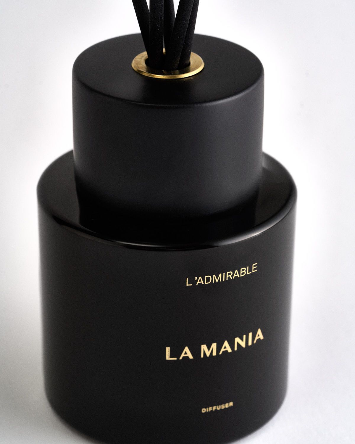 a black bottle with a gold top and black sticks sticking out of it