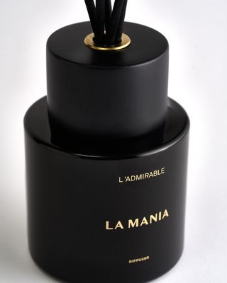 a black bottle with a gold top and black sticks sticking out of it