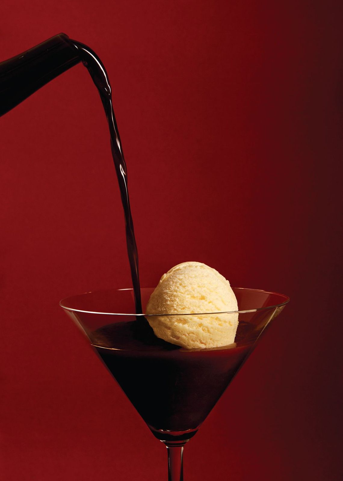 a scoop of ice cream being poured into a martini glass
