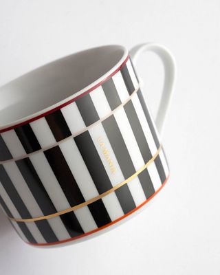 a black and white striped coffee cup with gold trim