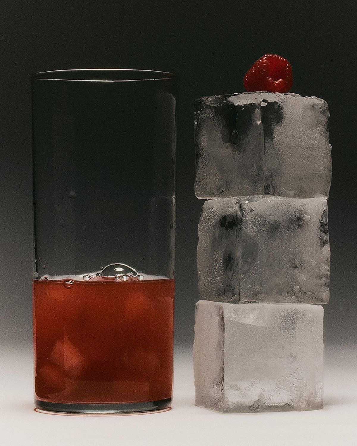 a glass of ice with a raspberry on top