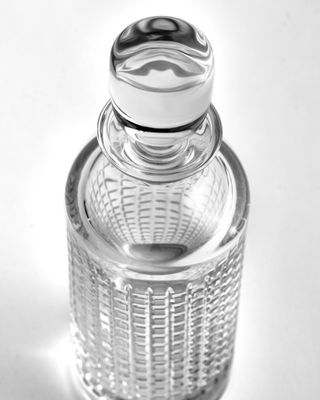 a glass bottle with a metal top on a white surface
