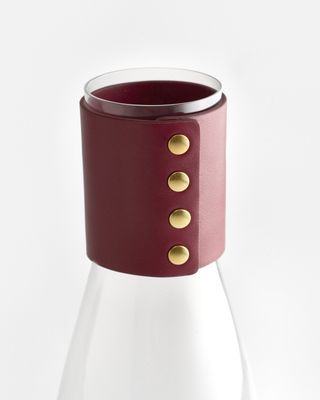 a white vase with a red leather cuff