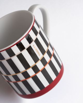 a black and white striped coffee cup with a red rim